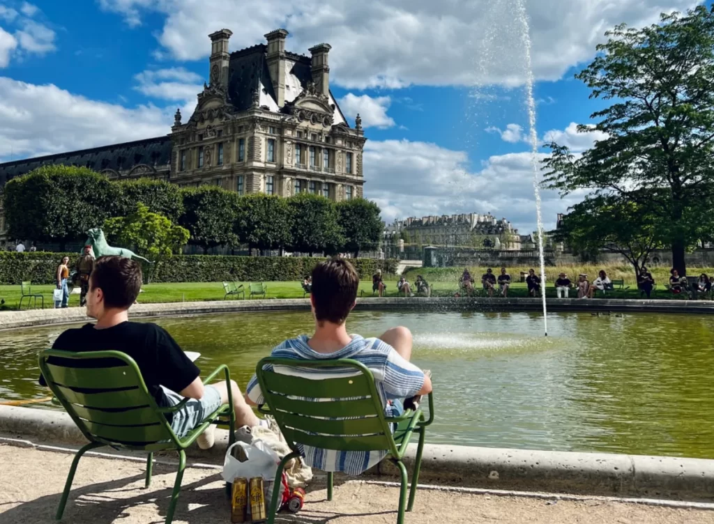 Pessoas relaxando nas cadeiras verdes ao redor do lago dos Jardins de Luxemburgo em Paris em um dia ensolarado