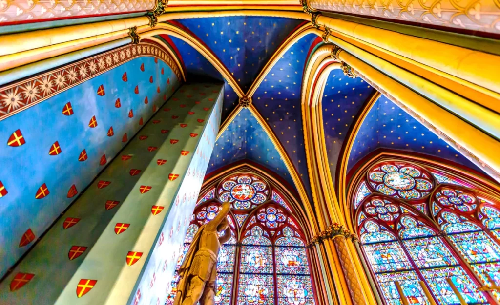 Teto gótico da Catedral de Notre-Dame de Paris com abóbadas pintadas em azul e dourado e vitrais históricos