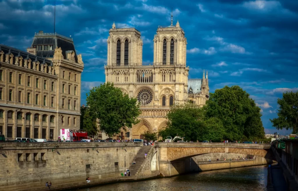 Fachada da Catedral de Notre-Dame de Paris com torres góticas e rosácea central às margens do rio Sena