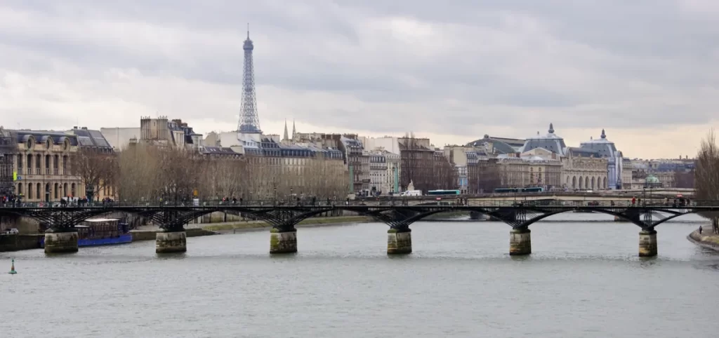 Ponte sobre o rio Sena em Paris com a Torre Eiffel ao fundo, mostrando a paisagem urbana clássica da capital francesa