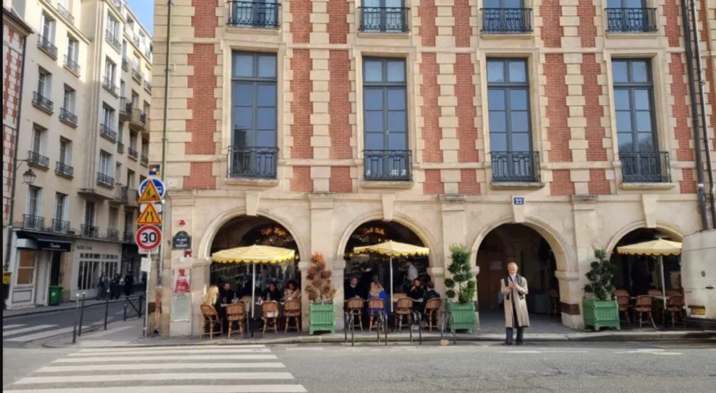 Café sob as elegantes arcadas da Place des Vosges, em Paris.