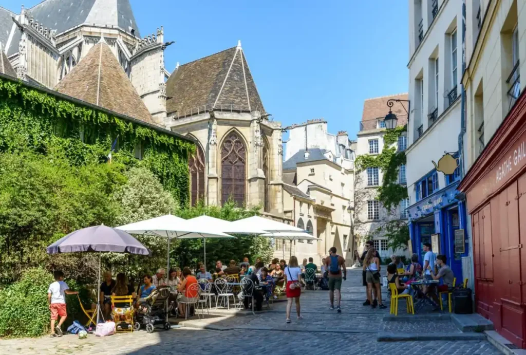 Café charmoso em uma rua histórica de Paris, cercado por arquitetura tradicional.