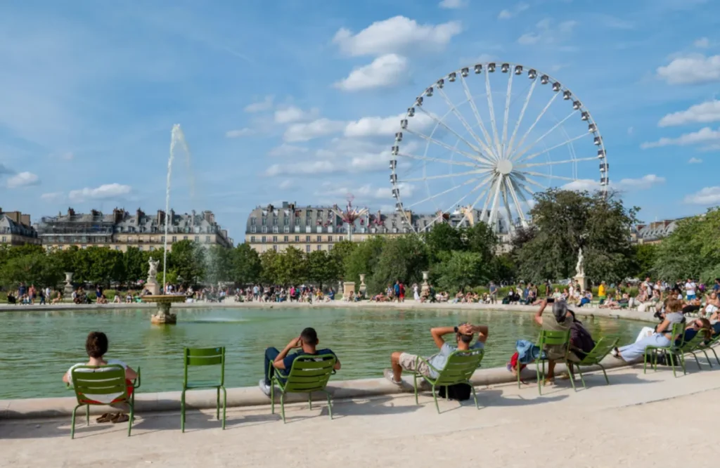 Um dia ensolarado no Jardim das Tulherias, entre o lago, as famosas cadeiras verdes e a paisagem parisiense.