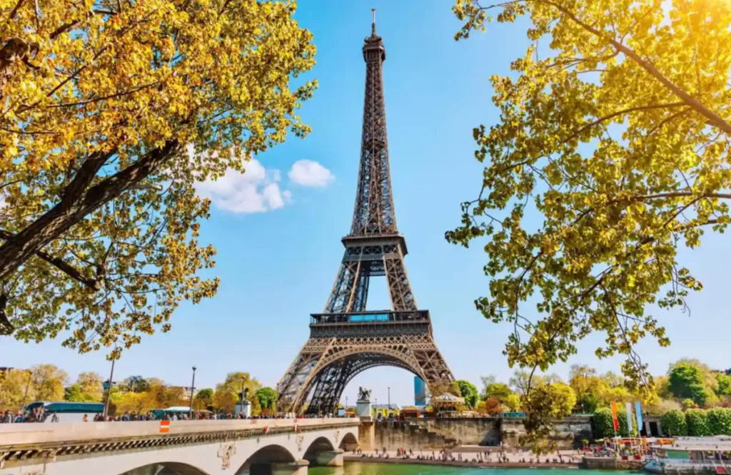 A Torre Eiffel entre as cores douradas do outono, próxima à Ponte de Iéna e às margens do Sena.