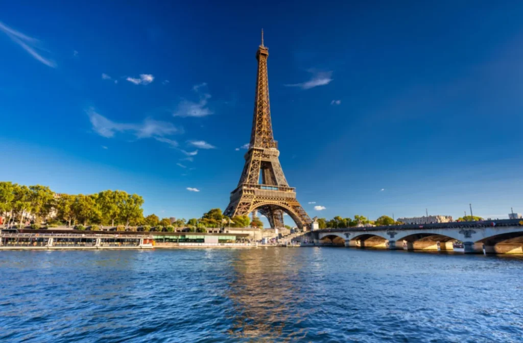 Vista clássica da Torre Eiffel às margens do Rio Sena e da Ponte de Iéna em um dia de céu azul.